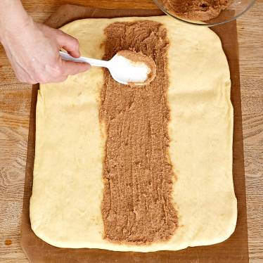 2. Kavla ut degen till en rektangel på ett mjölat bakplåtspapper. Bred ut fyllningen i mitten av degen.