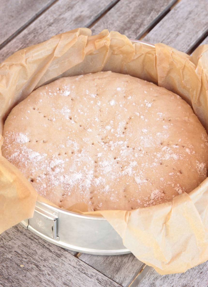 2. Tryck ut degen till en rund kaka i en form, ca 24 cm i diameter klädd med bakplåtspapper (utan att jäsa). Nagga degen med en gaffel och strö över lite mjöl. Låt degen jäsa under bakduk i ca 1 tim. Sätt ugnen på 250 grader. 