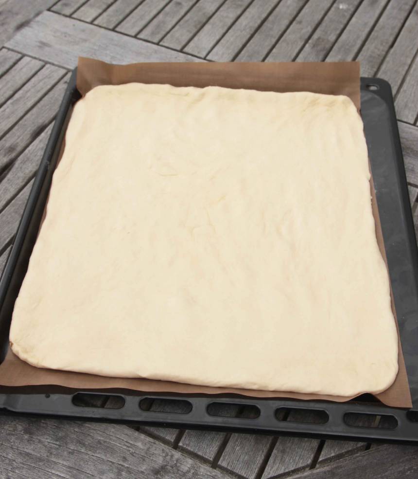 3. Tryck ut degen på en ugnsplåt med bakplåtspapper. Låt degen jäsa under bakduk i ca 30 min. Sätt ugnen på 220 grader.