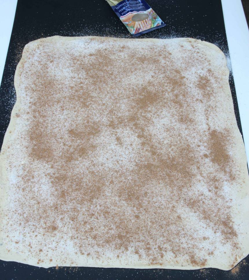 2. Kavla ut degen till en rektangel, ½–1 cm tjock, på ett mjölat bakbord. Bred ut smöret på degen och strö över socker och pepparkakskrydda. 