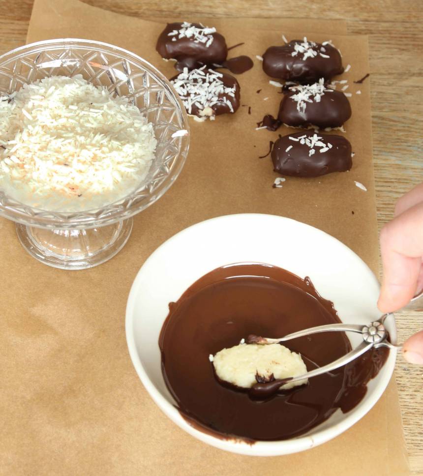 3. Doppa bitarna i smält choklad och lägg dem på ett bakplåtspapper. Strö över riven kokos. Låt dem stelna i kylen. Förvara konfekten i kylen i en burk med tätslutande lock.