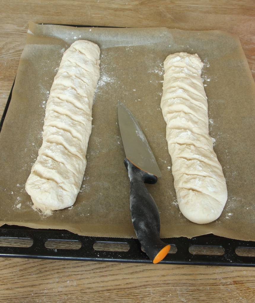 3. Lägg baguetterna på en ugnsplåt klädd med bakplåtspapper. Skär sneda snitt i baguetterna med en vass kniv. Låt dem jäsa under bakduk i ca 30 min. Sätt ugnen på 250 grader. 