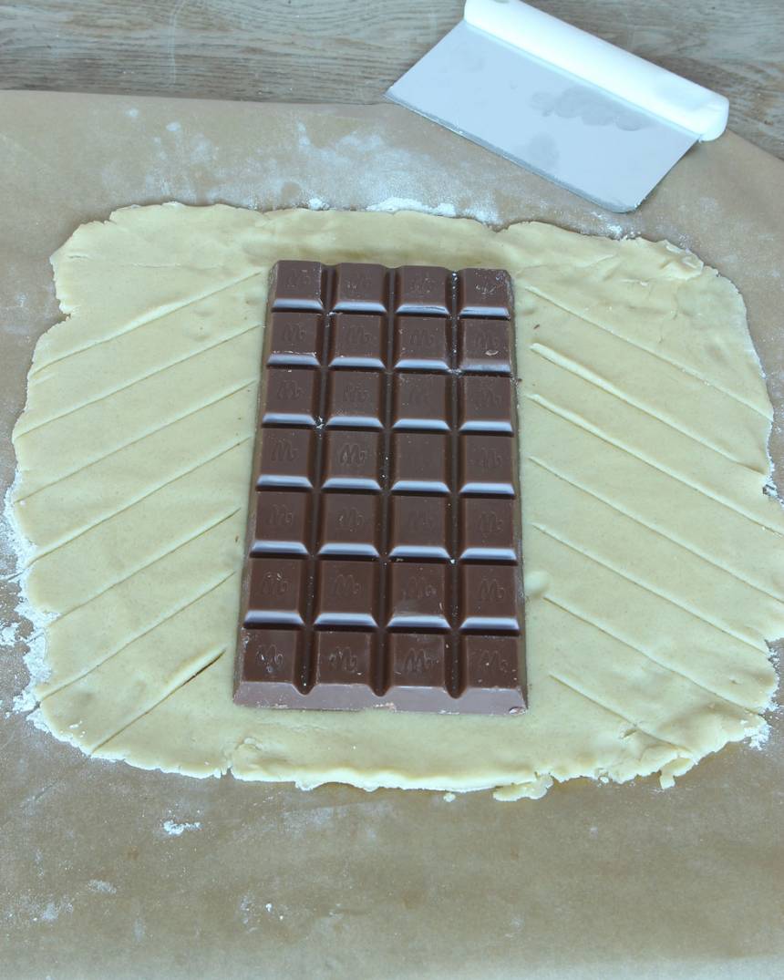 3. Lägg chokladkakan ovanpå degen. Skär kanterna i sneda flikar. 