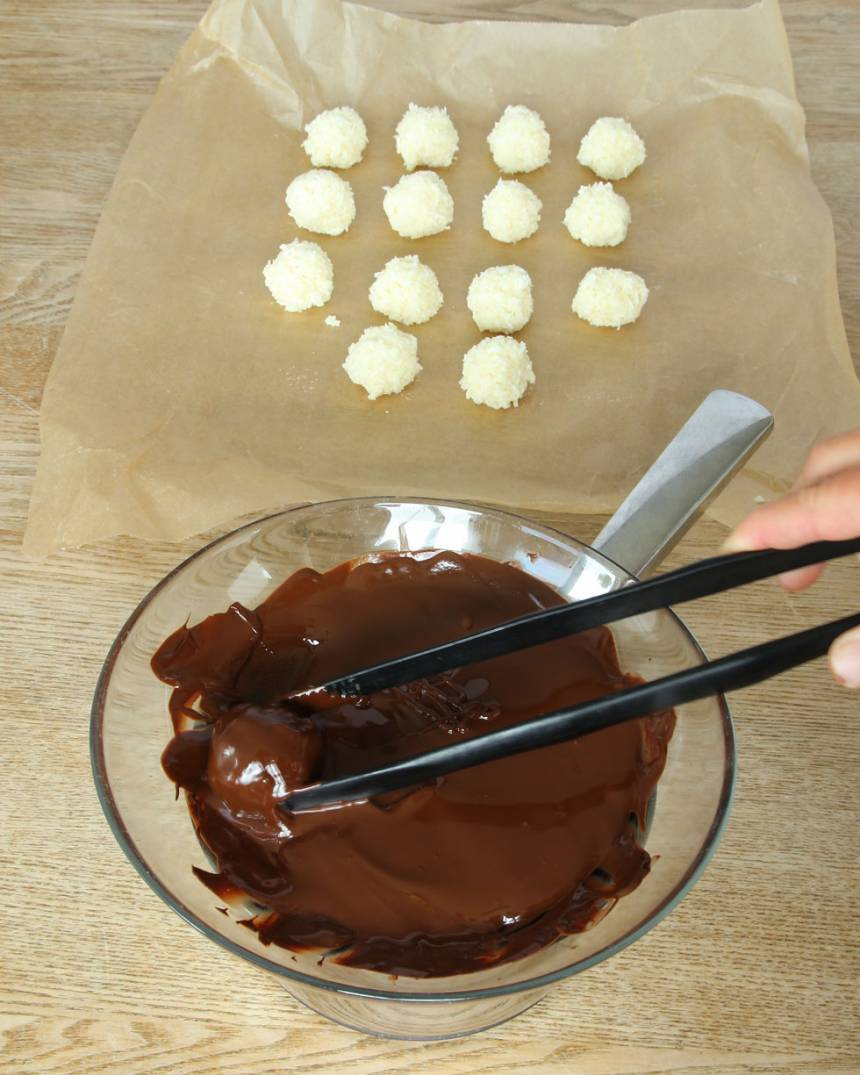 4. Doppa kokosbollarna i chokladen och lägg tillbaka dem på bakplåtspappret.
