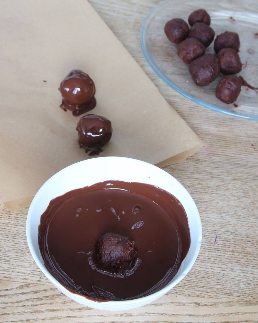 4. Forma runda bollar av chokladsmeten (ta gärna hjälp av två teskedar) och rulla dem i florsocker. Ställ dem i frysen i ca 30 min. Doppa dem i smält choklad. Lägg dem på ett bakplåtspapper och låt dem stelna i kylen. 