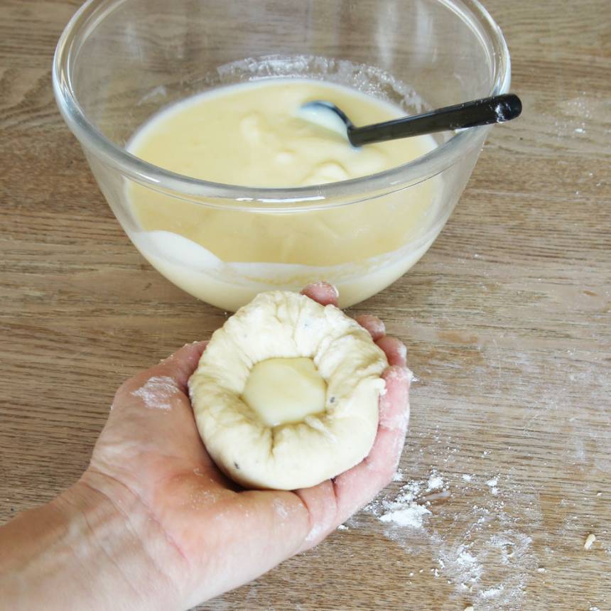 4. Platta ut bullarna, kupa handen och lägg rundeln i handen. Lägg en klick vaniljkräm i mitten. Nyp ihop bullen ordentligt utan att krämen rinner ut. 
