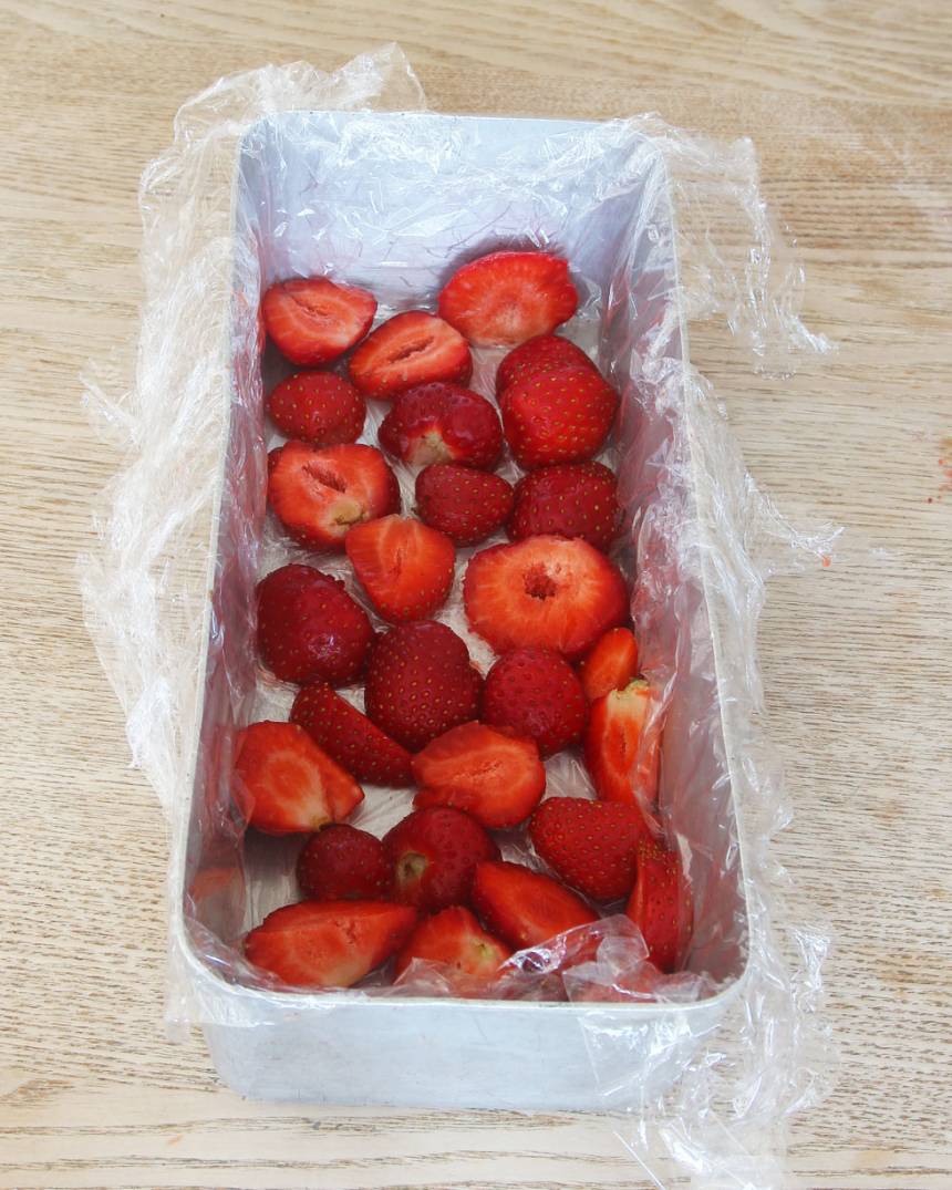 3. Plasta botten och kanterna på en limpform eller rund skål, ca 2 liter. Lägg jordgubbsskivorna i botten. 
