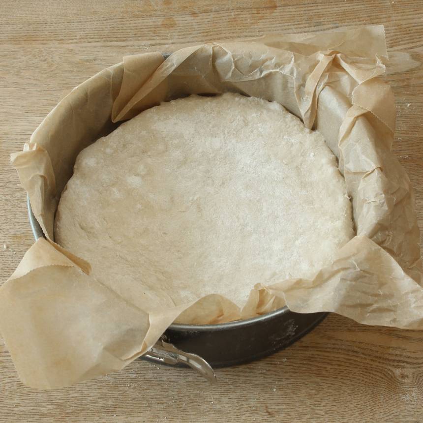 2. Tryck ut degen till en rund kaka i en form, ca 24 cm i diameter klädd med bakplåtspapper. Dela degen i 6–8 bitar med en degskrapa eller kniv. Täck formen med folié och ställ den i kylskåpet över natten. 
