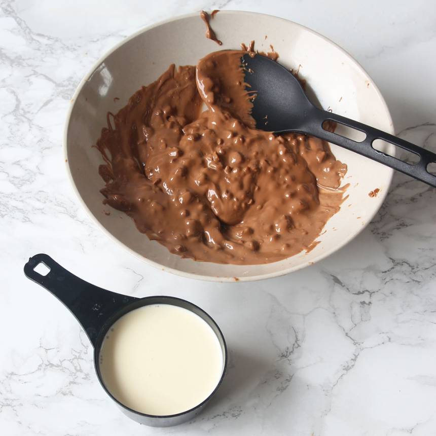 3. Smält chokladkakan i en skål över vattenbad. Häll i vispgrädden och rör om till en slät smet. (Tillsätt Daimen om du har Daim + mjölkchoklad). 