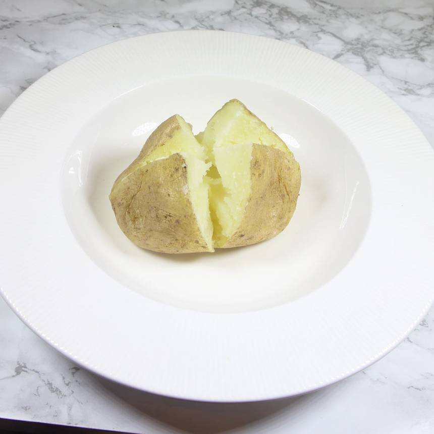 1. Stick några hål i potatisen med en potatissticka. 2. Kör potatisen på högsta effekt i 10–15 minuter, beroende på storlek. Den ska vara ordentligt mjuk rakt igenom. Om du kör flera potatisar på en gång tar det längre tid. 3. Skär ett kryss i potatisen med en vass kniv. Tryck ihop den med fingrarna från sidorna så att krysset öppnar sig. Lägg i en god röra eller en klick smör.
