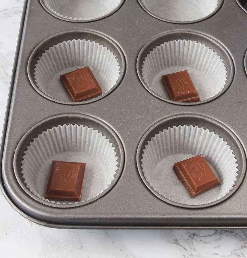 2. Ställ ut ca 15 muffinsformar på en plåt (eller i en muffinsform). Lägg en chokladbit i varje form. 